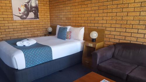 a hotel room with a bed and a couch at Royal Palms Motor Inn in Coffs Harbour
