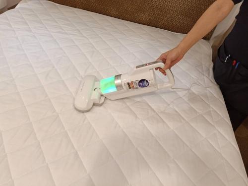 a person is putting a iron on a bed at Ximen Airline Hotel in Taipei