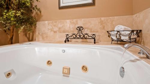 a white bath tub in a bathroom with a bench at Best Western Route 66 Glendora Inn in Glendora