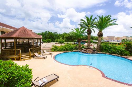 a swimming pool with a gazebo and palm trees at Best Western Pearland Inn in Pearland