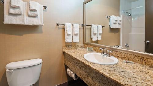 a bathroom with a toilet and a sink and a mirror at Best Western King George Inn & Suites in Surrey