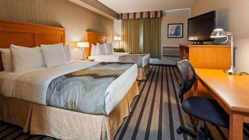 a hotel room with two beds and a desk at Best Western King George Inn & Suites in Surrey