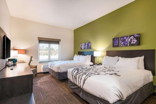 a hotel room with two beds and a flat screen tv at Sleep Inn Baxley in Baxley