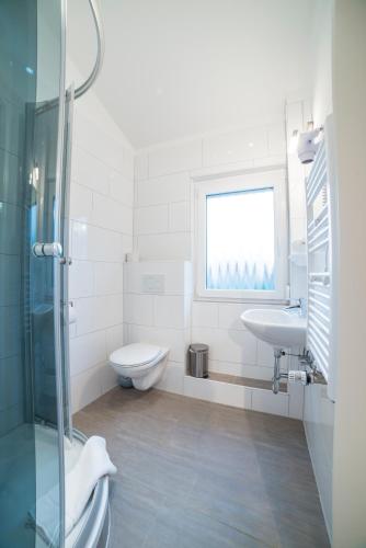 a white bathroom with a toilet and a sink at Schützenhaus Bondorf in Bondorf