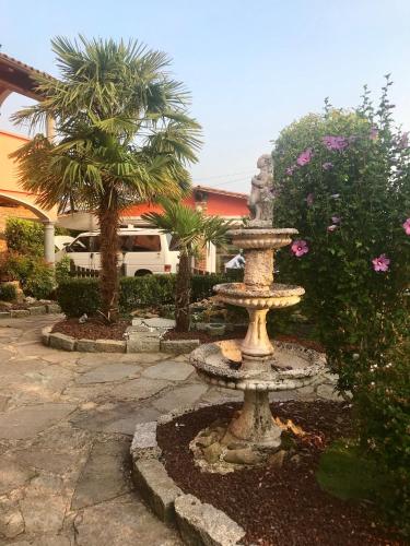 a stone fountain in a yard with palm trees at B&B Villa Botto in Cossato