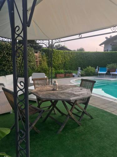 a table and chairs under an umbrella next to a pool at B&B Villa Botto in Cossato