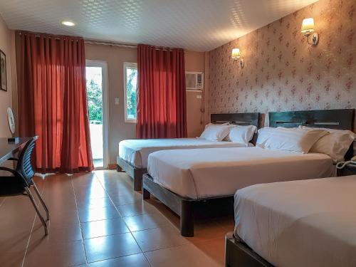 two beds in a hotel room with red curtains at Tagaytay Wingate Manor in Tagaytay