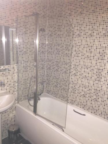 a bathroom with a bath tub and a sink at Heathrow Garden House - West Drayton, London - Benjamin Guest House in Yiewsley