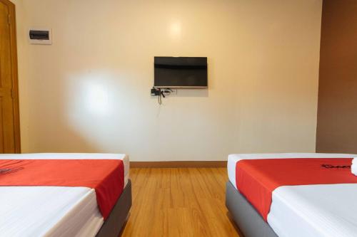 two beds in a room with a flat screen tv at RedDoorz Plus @ Starhomes Olivianville in Tarlac
