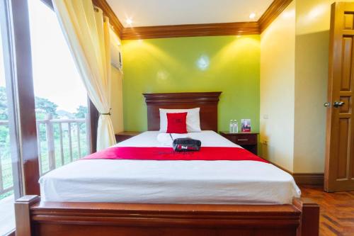 a bedroom with a large bed with a red pillow at RedDoorz Plus @ Starhomes Olivianville in Tarlac