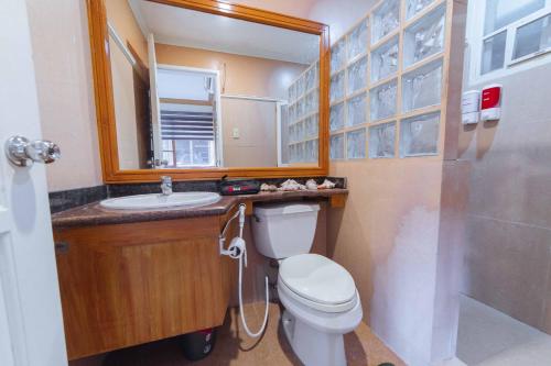 a bathroom with a toilet and a sink and a mirror at RedDoorz Plus @ Starhomes Olivianville in Tarlac