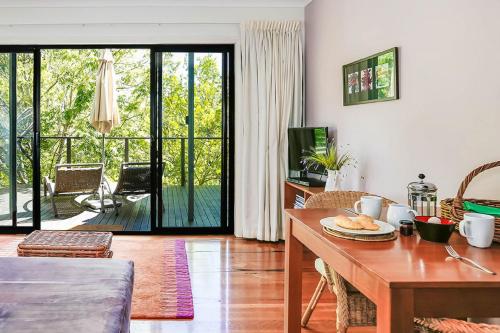 a living room with a dining room table with a view of a patio at Cloudsong Chalet 2 Close to the village centre in Kangaroo Valley