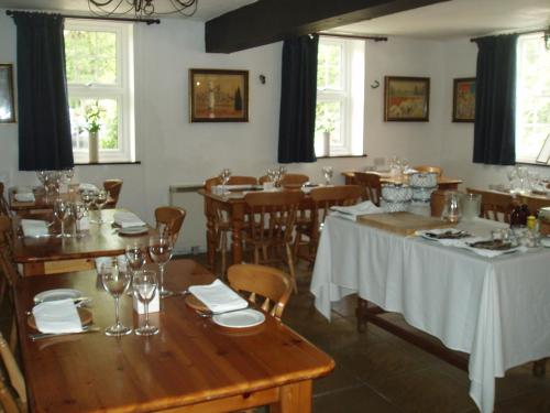 サーズフォードにあるThe Old Forge Seafood Restaurant and Bed and Breakfastの木製のテーブルと椅子、窓のあるレストラン