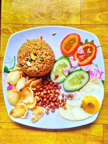 a plate of food with a fried egg and vegetables at Ira Bungalows Pulau Banyak in Alaban