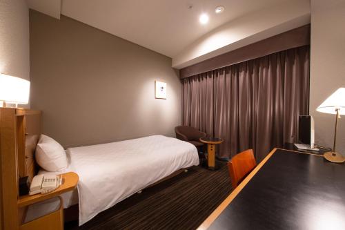 a hotel room with a bed and a desk with a phone at Hotel Nagoya Garden Palace in Nagoya