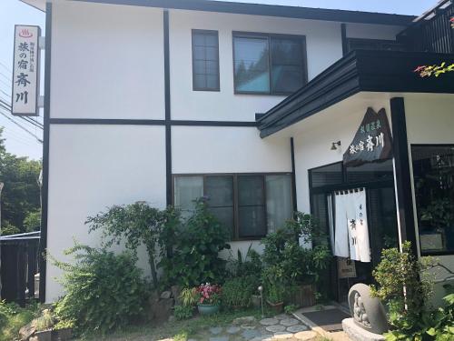 a white house with black windows and plants at Tabinoyado Saikawa in Kuroishi