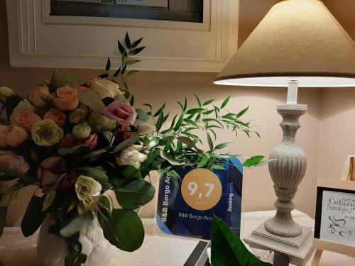 a vase of flowers sitting on a table next to a lamp at B&B Borgo Arcadia in Poiana Maggiore