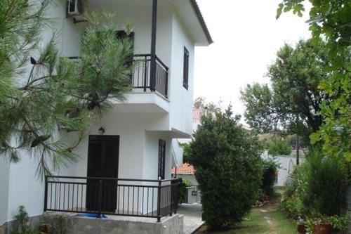 a white house with black balconies and trees at Pension Marina in Kinira