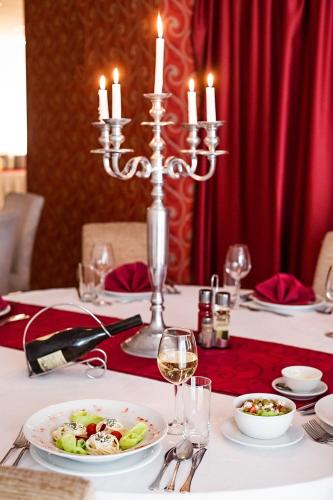 a table with a plate of food and candles on it at Hotel Putnik in Novi Sad