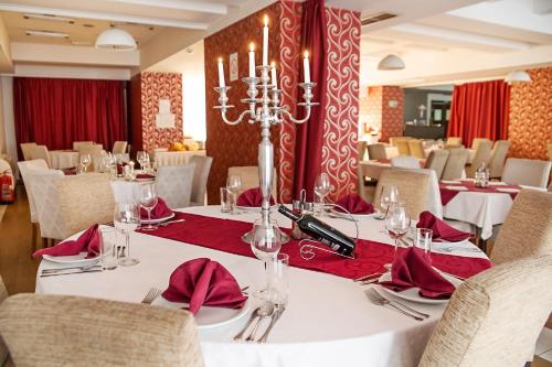 une salle à manger avec des tables blanches et des serviettes rouges dans l'établissement Hotel Putnik, à Novi Sad