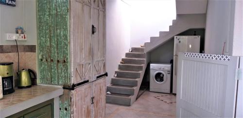 a laundry room with a staircase and a washing machine at Appartement Blue Coast in Mahébourg