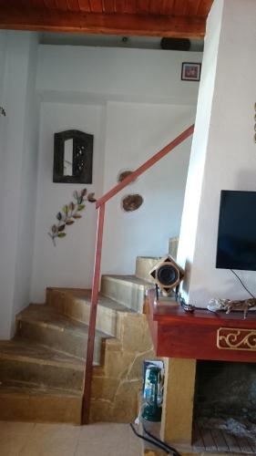 a living room with a staircase with a television at Mistatos Häuser "Fabrica" in Pévkoi