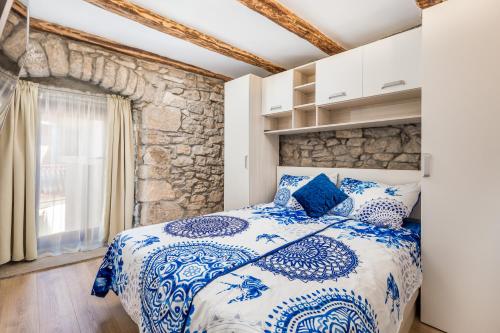 - une chambre avec un lit bleu et blanc et un mur en pierre dans l'établissement Rural holiday home Stankolina Opatija, à Jurdani