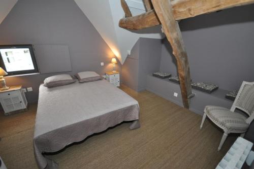 a bedroom with a bed and a chair and a television at Gîte de La Broderie in Bersée