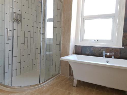 ein Bad mit einer Badewanne und einem Fenster in der Unterkunft Grandeur Holiday home, with free parking in Clacton-on-Sea