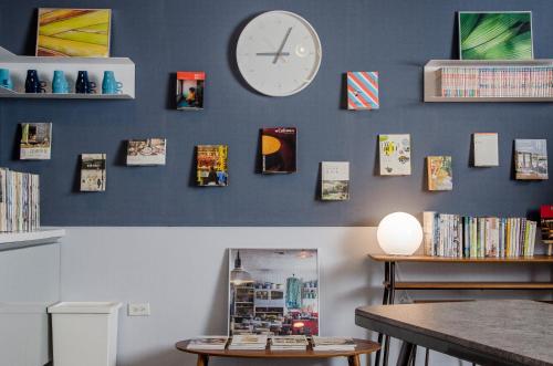 a wall with a clock and a table and books at Flying Backpacker in Yilan City