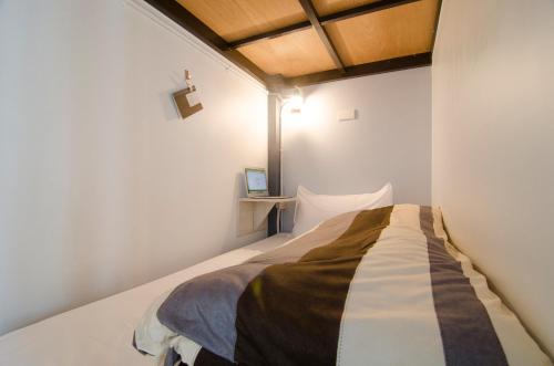 a bedroom with a bed in a white room at Flying Backpacker in Yilan City