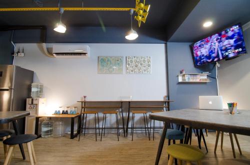 a dining room with tables and chairs and a tv at Flying Backpacker in Yilan City