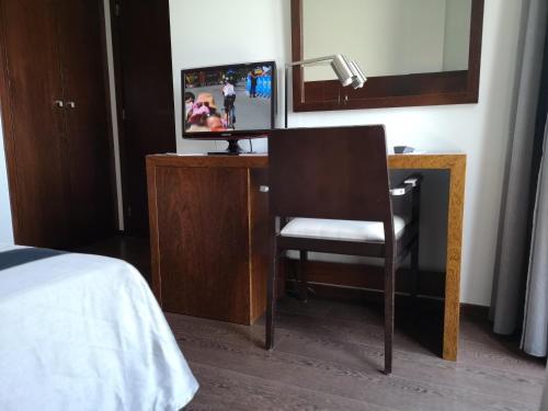 a bedroom with a desk with a chair and a mirror at Hotel Portas De Santa Rita in Ermesinde