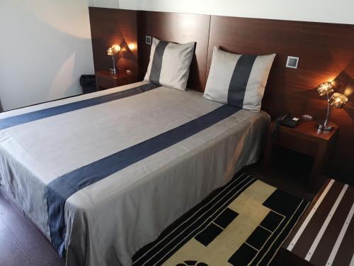 a bedroom with a large bed with a wooden headboard at Hotel Portas De Santa Rita in Ermesinde