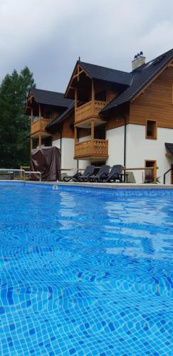 a large blue swimming pool in front of a building at Szarlotka in Szczawnica