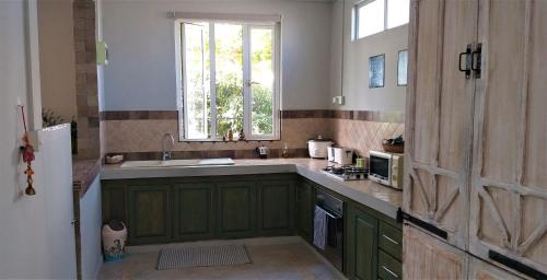 a kitchen with green cabinets and a window at Appartement Blue Coast in Mahébourg