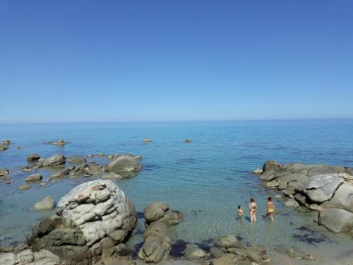 people standing in the water on a rocky beach at B&B Centrale in Tortolì