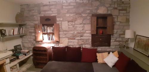 a living room with a couch and a stone wall at Les Villas de Qeparo in Qeparo