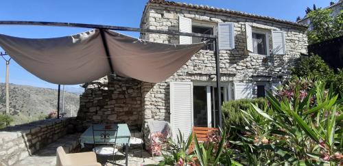 a stone house with an umbrella in front of it at Les Villas de Qeparo in Qeparo