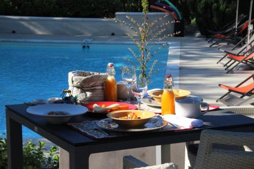 una mesa con comida y bebidas junto a una piscina en Le Hameau Fleur de Pierres , Chambres d'Hôtes , Gite et Restaurant Table d'Hôtes, en Murs