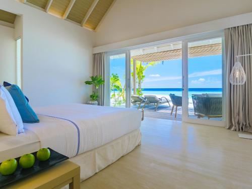 a bedroom with a bed and a view of the ocean at Baglioni Resort Maldives - Luxury All Inclusive in Dhaalu Atoll