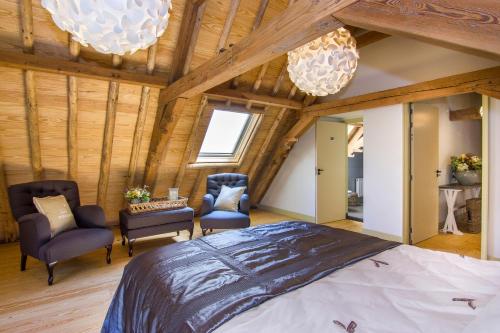 a bedroom with a large bed and two chairs at Gasterij Leyduin in Vogelenzang