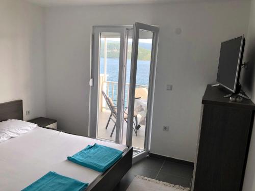 a bedroom with a bed and a television and a balcony at Apartments Lukrecia in Neum