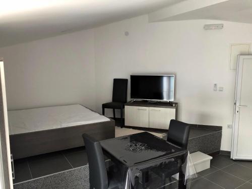 a bedroom with a bed and a tv and a table at Apartments Lukrecia in Neum