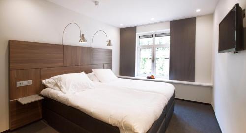 een slaapkamer met een groot bed en een raam bij Hotel Café Restaurant De Ploeg in Varsseveld