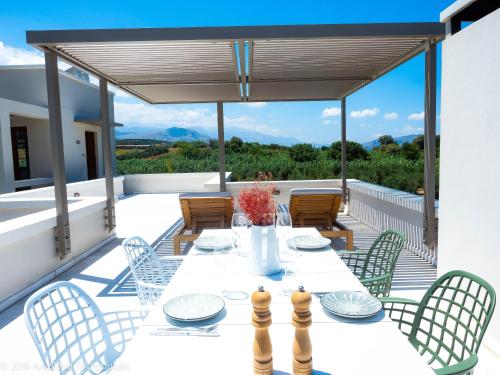 un patio con mesa y sillas en una terraza en Mikro Livadi Special Lodges - Has an Eco Salt water pool - 150m from the beach en Episkopí- Rethimno