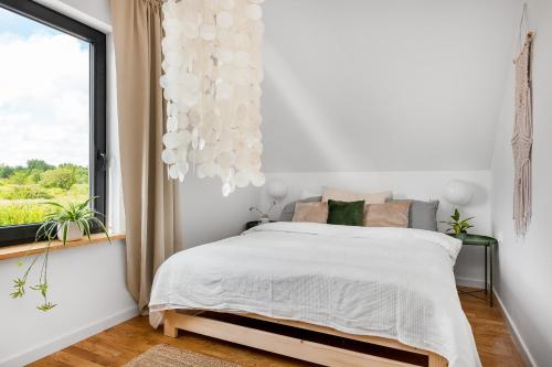 biała sypialnia z łóżkiem i oknem w obiekcie Domki ROSSE niedaleko plaży w Jastrzębiej Górze