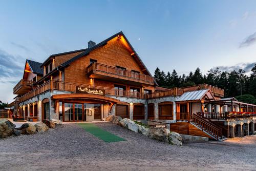 ベルモンにあるHotel Restaurant Mont Champ du Feuのポーチとバルコニー付きの大きな木造家屋