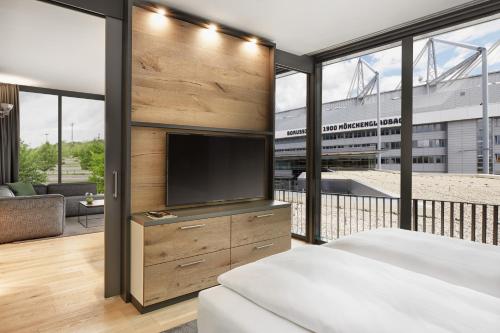 a hotel room with a large bed and a television at H4 Hotel Mönchengladbach im BORUSSIA-PARK in Mönchengladbach