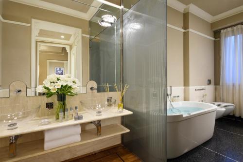 a bathroom with a tub, sink, and shower at Brunelleschi Hotel in Florence
